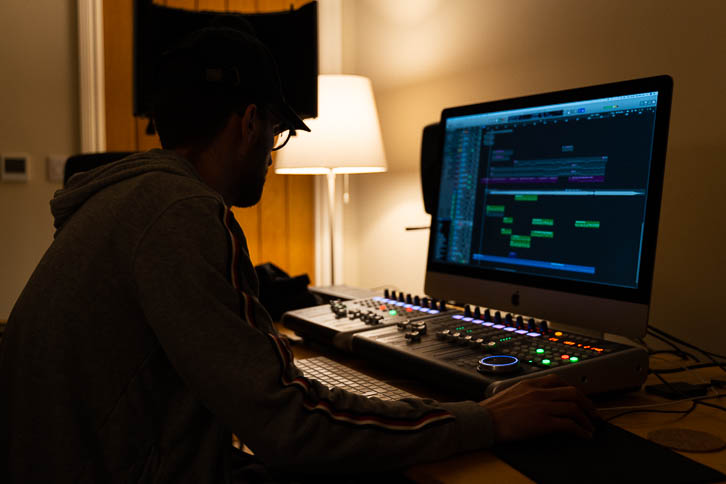 Alastair sitting behind music iMac in dark bedroom studio