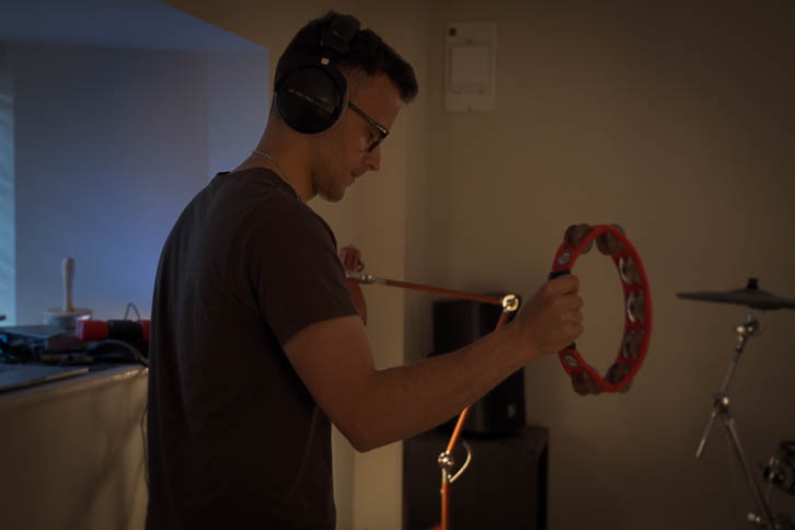 Gavin playing tambourine in a dark bedroom music room