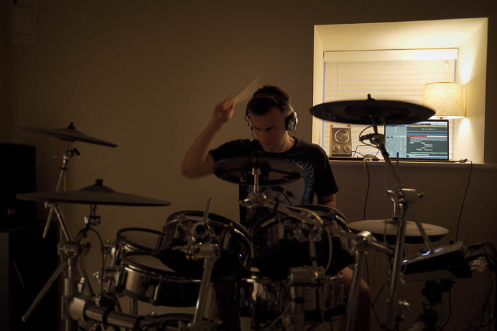 Gavin recording drums in a dark bedroom music room
